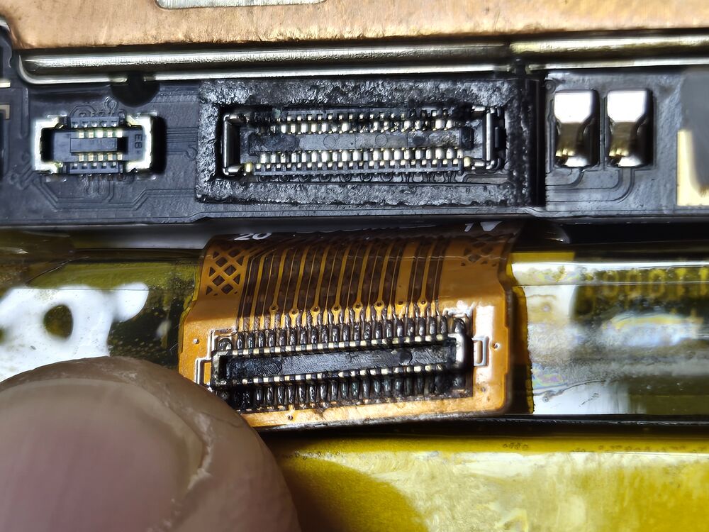 Connecteur de carte mère oxydé sur un Oppo Reno 4Z, dépôts noirs entre les broches