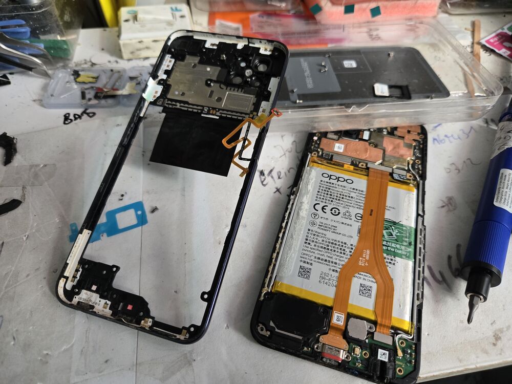 Oppo Reno 4Z démonté à l'atelier : châssis d'un côté, carte mère et batterie de l'autre